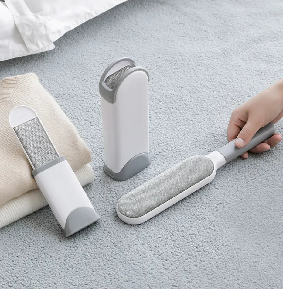 Two Electrostatic Hair Removal Brushes with container on a carpet with a hand holding one of the brushes.