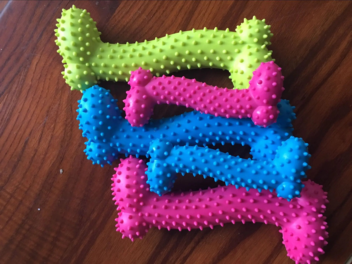 Five bone shaped doggy chew toys with a spiked surface in various colors and sizes.
