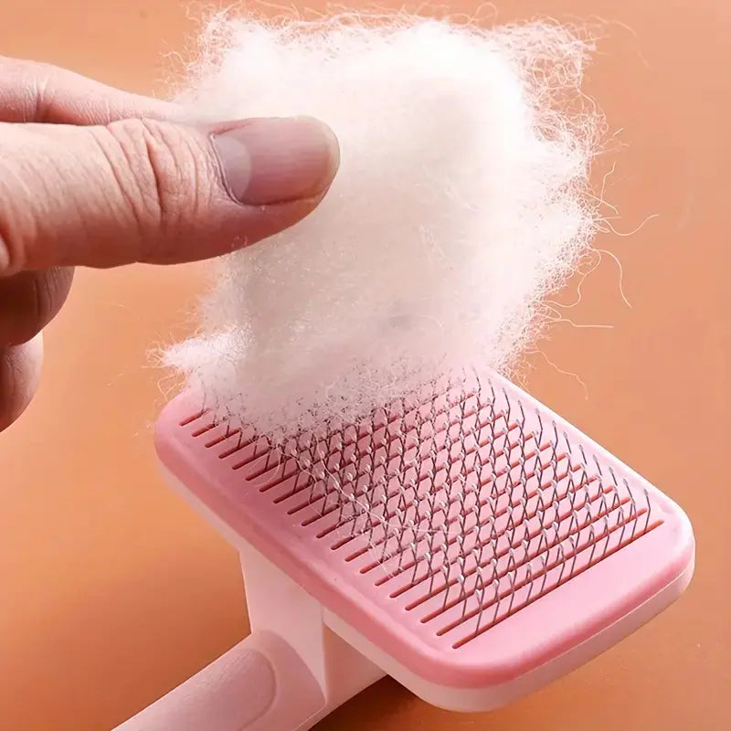Pink (Rose) colored Pet Hair Removal Comb being cleaned. Ejection button releases collected hair for easy cleaning.