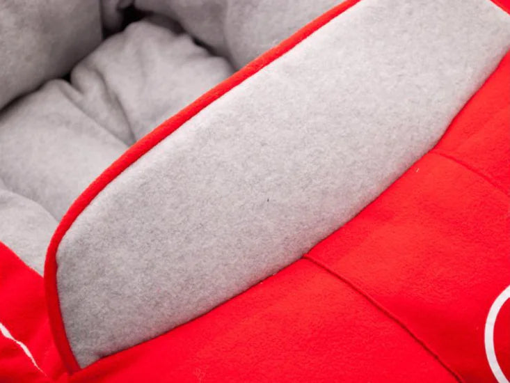 Close up of Mercedes Benz themed red and gray car-shaped pet bed.