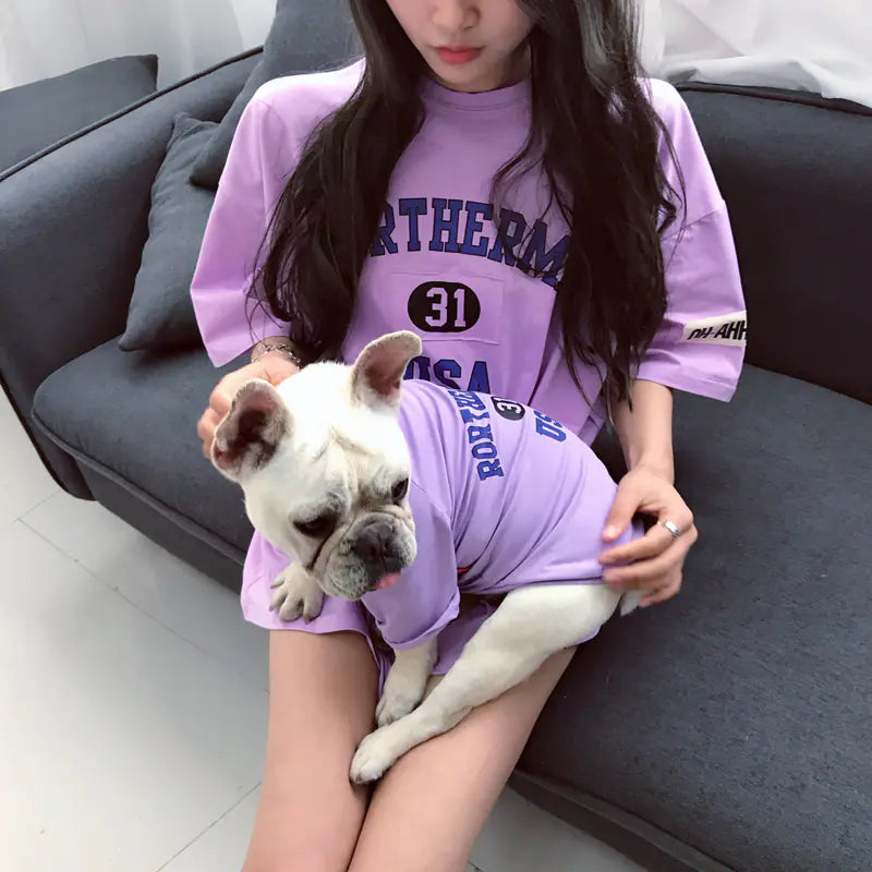 Pet parent and dog relaxing comfortably while wearing matching Purple (Lavender) cotton shirts with 'Rortherme USA' text written in blue.