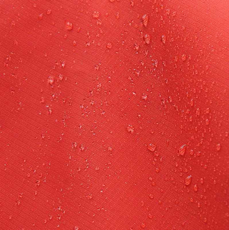 Red fabric with water droplets on a close-up view showing how the material repels water.
