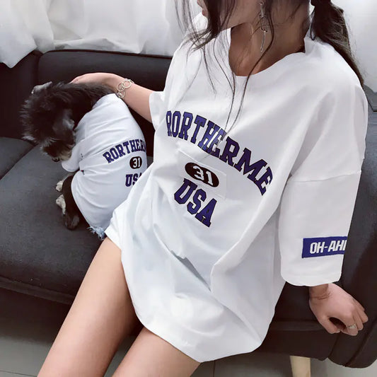 Pet parent and dog relaxing comfortably while wearing matching White (Pearl) cotton shirts with 'Rortherme USA' text in blue.