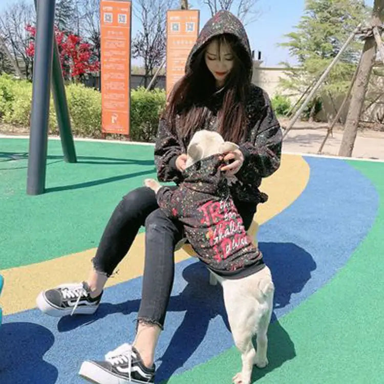 Parent and doggie wearing matching Black (Matte) hoodies with colorful splatter & text written on the back, twinning for a dog walk.