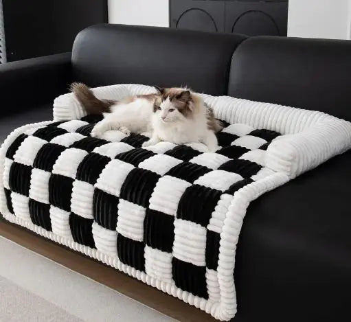 Cat lying on a black and white checkered pet sofa cover on a black leather couch.
