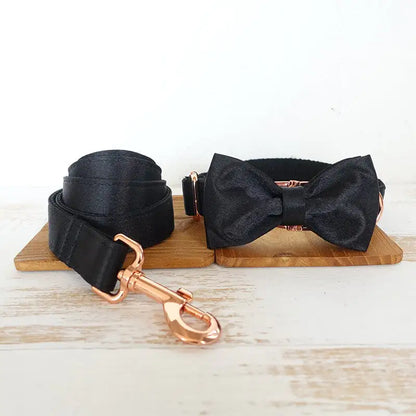 Stylish doggie Black (Midnight) bow tie on a wooden block with a light wood background with rose gold matching leash