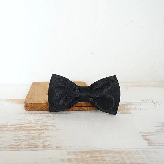 Stylish doggy Black (Midnight) bow tie on a wooden block with a light wood background