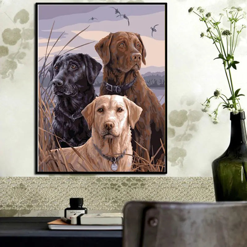 Completed diamond painting art kit featuring three dogs of different breeds enclosed in a black frame and hung on a wall.