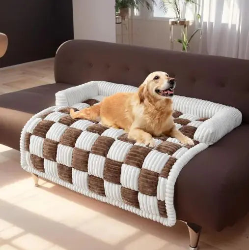 Dog relaxing on a brown and white checkered pet sofa cover on a brown couch.