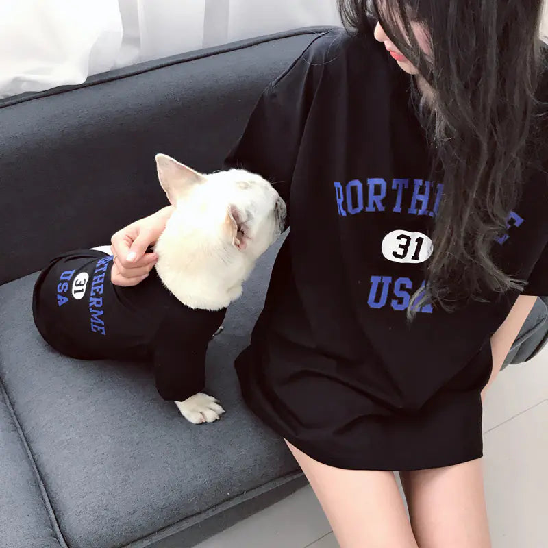 Pet parent and doggie relaxing comfortably while wearing matching Black (Midnight) cotton shirts with 'Rortherme USA' text written in blue.